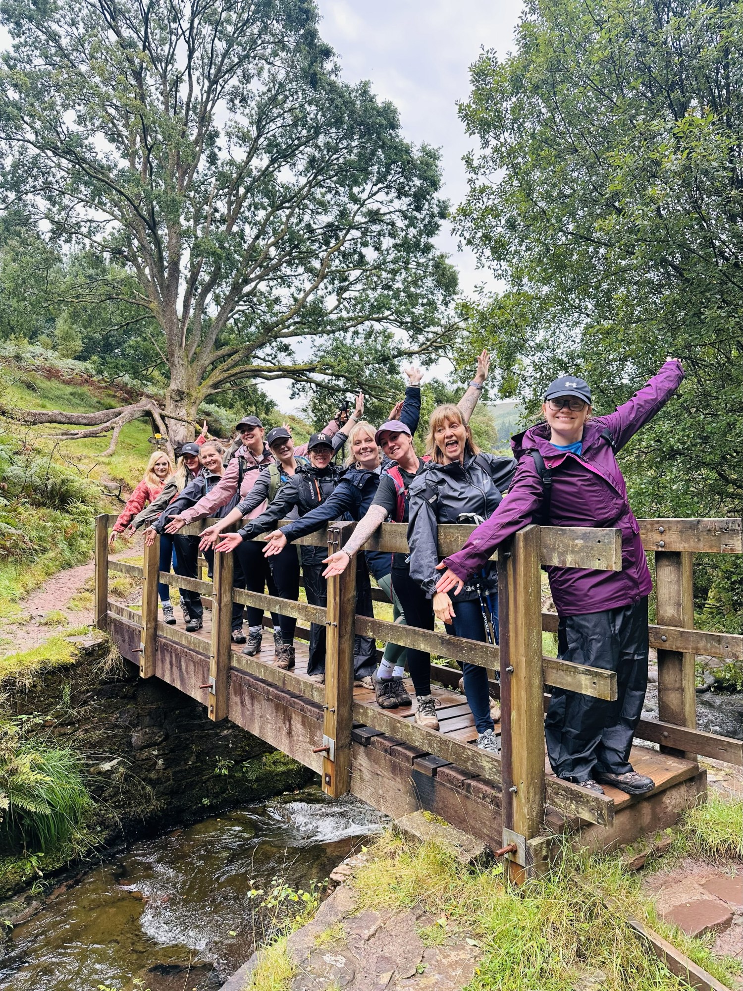 Group of people posing on a wooden bridge in a forested area.