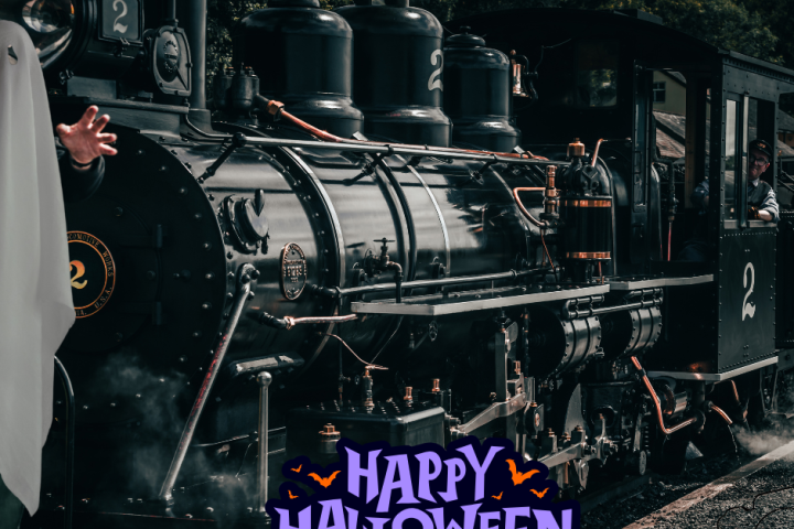 Steam train with 'Happy Halloween' text and a person in ghost costume on the left.