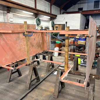 Metal sheets clamped on sawhorses in a workshop setting.