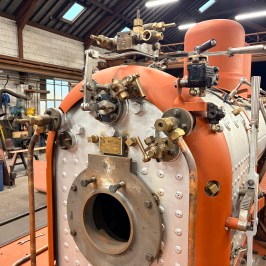 Close-up of a steam locomotive boiler under maintenance in a workshop.