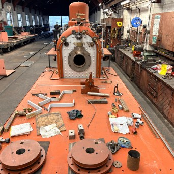 Workshop with a steam engine under construction, tools scattered around on a workbench.