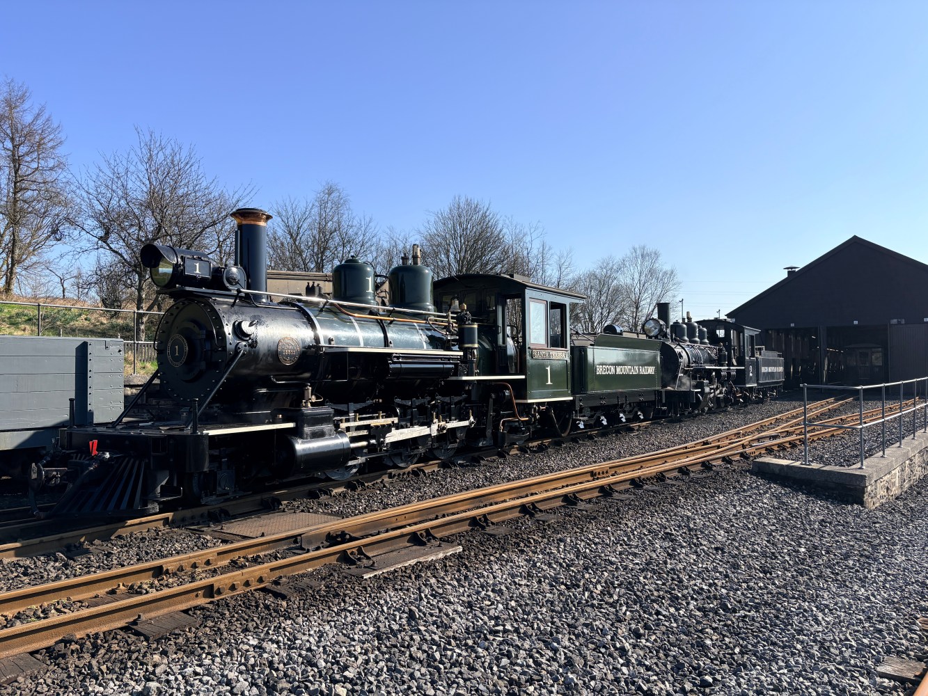 Historic steam locomotive on railway tracks under clear blue sky.