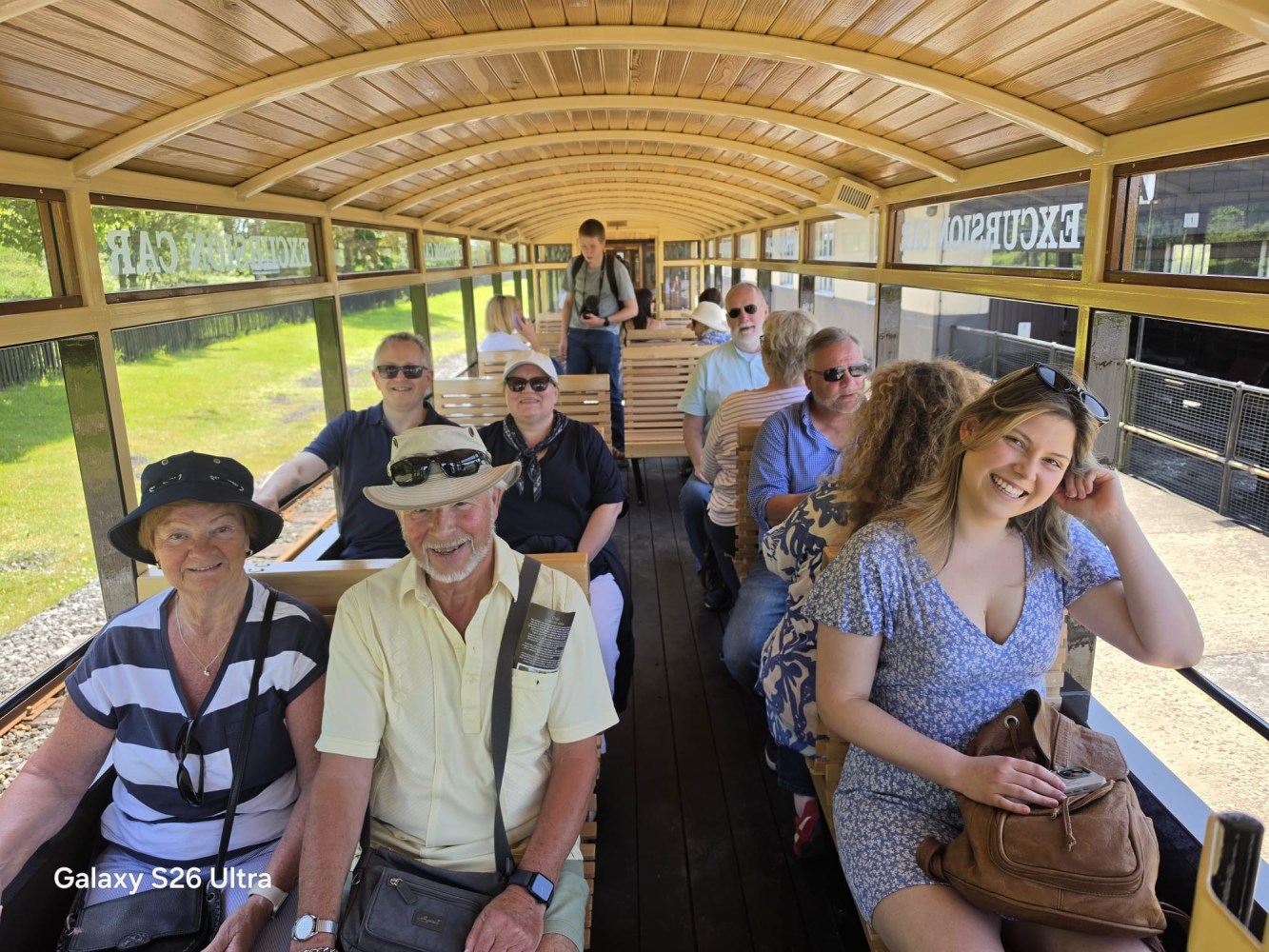 Group of people smiling inside a wooden open-air trolley.