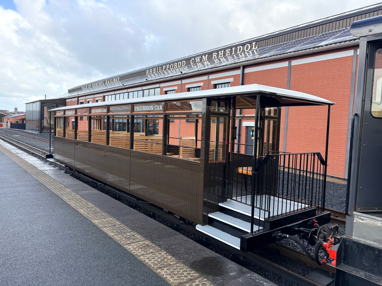 Vintage train carriage at a platform in front of a station.