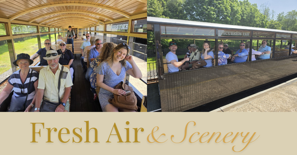 People sitting in open carriage on vintage train, enjoying sunny day.